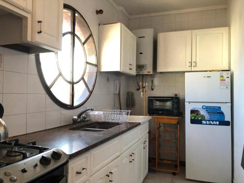 cocina con armarios blancos y nevera blanca en Departamento de un dormitorio en pleno centro de Carlos Paz en Villa Carlos Paz