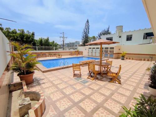 a patio with a table and umbrella next to a pool at Hermoso departamento con vista la playa murciélago in Manta