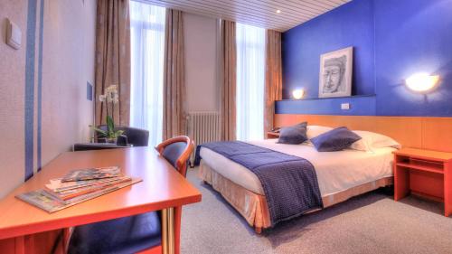 a hotel room with a bed and a desk at Hotel Le Terminus in Mons