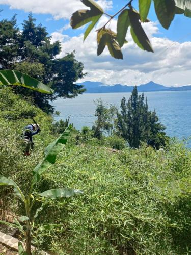 a person walking on a hill next to the water at Peaceful Hideaway in Santa Cruz La Laguna