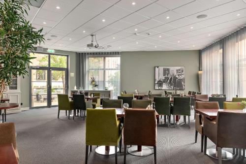 a dining room with tables and chairs and windows at Best Western Plus Grand Hotel in Halmstad