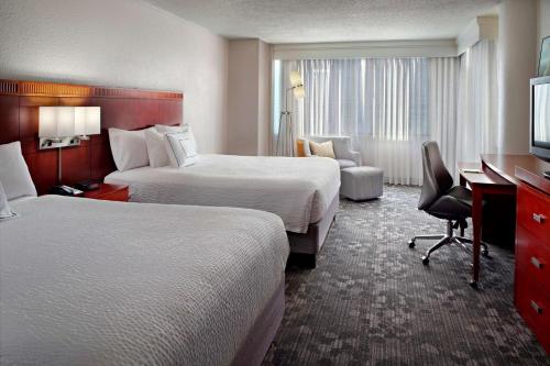 a hotel room with two beds and a desk at Sonesta Select Atlanta Cumberland Galleria in Atlanta