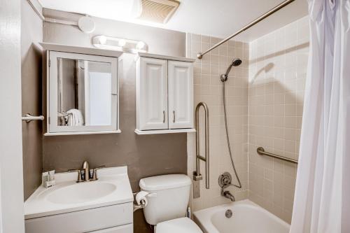 a bathroom with a white toilet and a sink and a shower at Palm Rising in Palm Beach