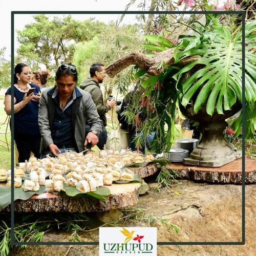 a group of people standing around a table with food at Uzhupud Garden Hotel & Lodge in Paute