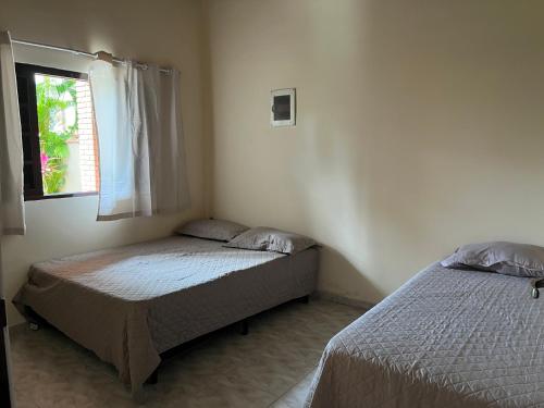 a bedroom with two beds and a window at Casa Paraíso - Cond Costa do Sol- Bertioga in Bertioga