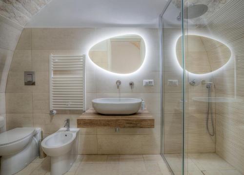 een badkamer met een wastafel, een toilet en een spiegel bij Home Pedra in Ceglie Messapica
