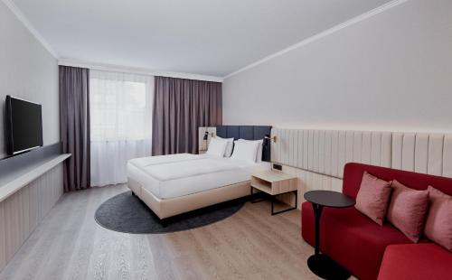 a hotel room with a bed and a red couch at Crowne Plaza Hamburg-City Alster by IHG in Hamburg
