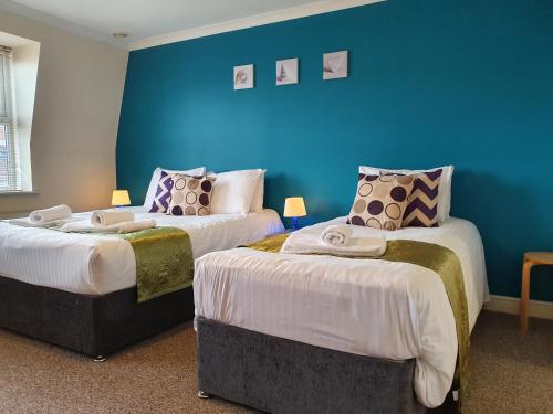 Una habitación con dos camas y una pared azul. en Old Town Apartments, en Swindon