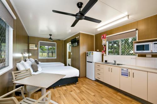 a bedroom with a bed and a kitchen with a table at Bali Hai Child Free Holiday Park Mission Beach in Mission Beach