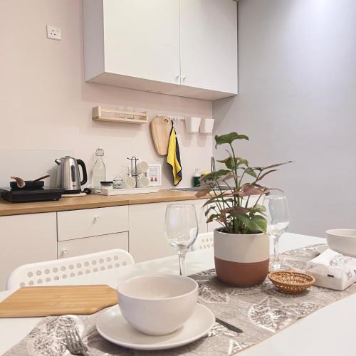a kitchen with a table with glasses and a plant at AruSuites Tanjung Aru Kota Kinabalu By LAXZONE in Kota Kinabalu