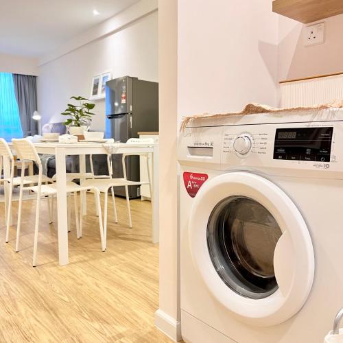 a washing machine in a room with a table at AruSuites Tanjung Aru Kota Kinabalu By LAXZONE in Kota Kinabalu