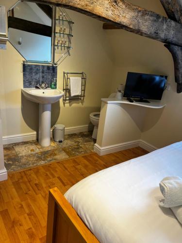 a bathroom with a sink and a toilet and a bed at The Vale Hotel in Cricklade