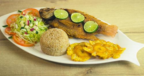 Hotel Los Veleros Santa Marta في سانتا مارتا: طبق من الطعام به سمك وخضروات على طاولة