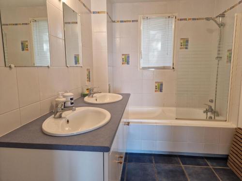 uma casa de banho com 2 lavatórios, um chuveiro e uma banheira. em Holiday home with sea view, Pordic em Pordic