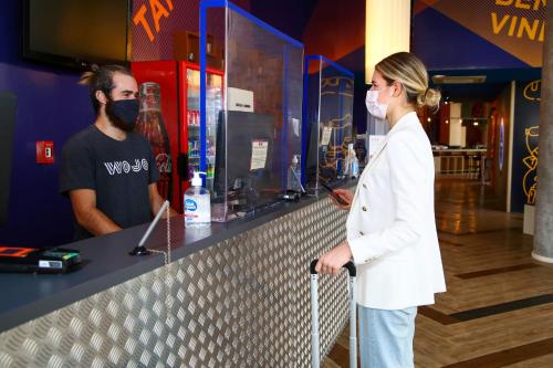 a woman wearing a mask standing next to a counter at ibis budget Tambore in Barueri