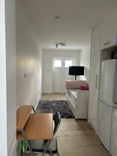 a small room with a table and a bed at Lovely en-suite studio with kitchen and free parking with walking distance to tube station and short train ride to central London!! in Northwood