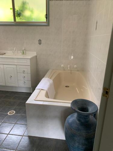 a bathroom with a bath tub and a vase at Grandmas Cottage Fairmont in Woodhill