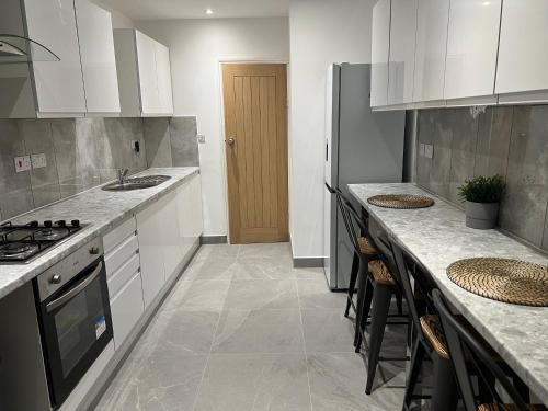 uma cozinha com armários brancos e um forno com placa de fogão em BEAUTIFUL ROOMS ONLY FEW STEPS AWAY FROM BRUCE GROVE TOTTENHAM STADIUM em Londres