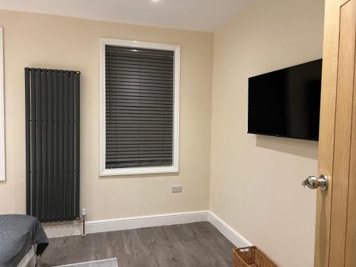 a bedroom with a flat screen tv and a window at BEAUTIFUL ROOMS ONLY FEW STEPS AWAY FROM BRUCE GROVE TOTTENHAM STADIUM in London