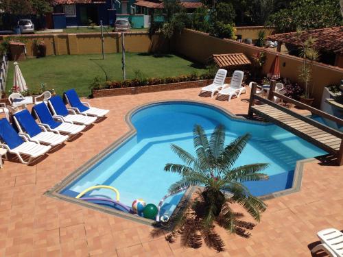 a swimming pool with lounge chairs and a palm tree at Pousada dos Corais in Itaúnas