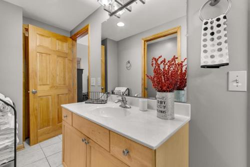 uma casa de banho com um lavatório e um vaso com flores vermelhas em Casa Tweetsie em Banner Elk