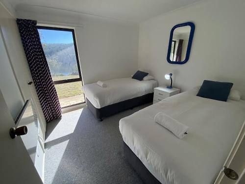 a room with two beds and a mirror and a window at Banksia 1 in Jindabyne