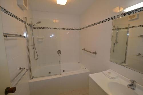 a bathroom with a shower and a tub and a sink at Banksia 1 in Jindabyne