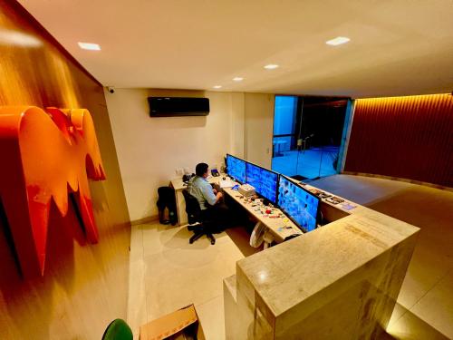 a man sitting at a desk in a room with monitors at Flat perfeito no coração de Boa Viagem in Recife