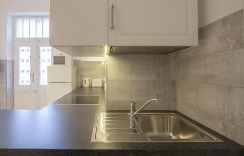 una cocina con fregadero de acero inoxidable y armarios blancos en City Centre Apartment with 3 Bathrooms en Budapest