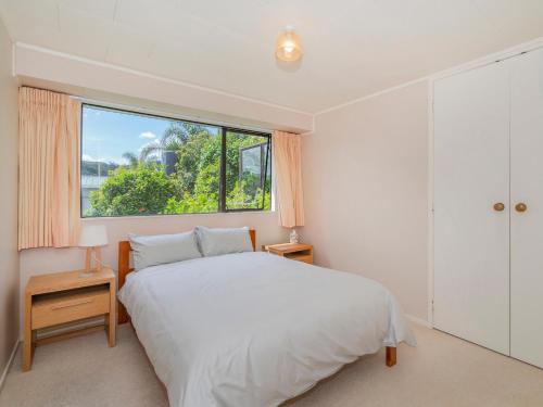 a bedroom with a bed and a large window at Treasure on Chestnut - Tairua Holiday Home in Tairua