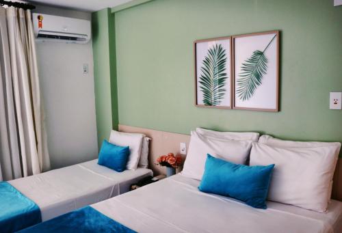 2 Betten in einem Zimmer mit grünen Wänden und blauen Kissen in der Unterkunft Grand Lençóis Flat in Barreirinhas