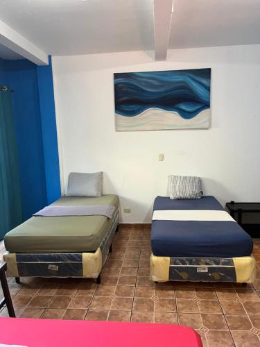 2 camas en una habitación con paredes azules y blancas en Casa Makoi en Tamanique