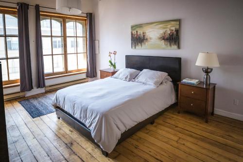 a bedroom with a bed and a lamp and windows at Le 402 in Montréal