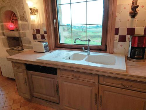 eine Küche mit einem Waschbecken und einem Fenster in der Unterkunft Breton granite stone house with fantastic sea views in Saint-Pol-de-Léon