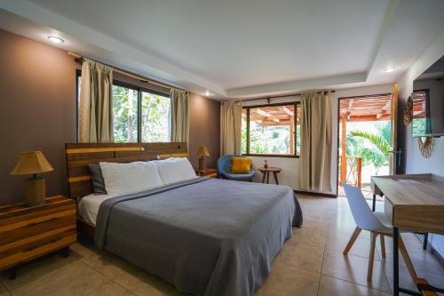 um quarto com uma cama, uma secretária e janelas em Hotel Arco Iris em Tamarindo