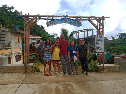 a family poses for a picture in front of a welcome sign at Titaays Surfers Inn in Baras
