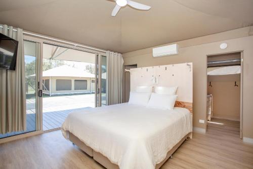 a bedroom with a large bed and a balcony at Crowdy Bay Eco Resort in Harrington
