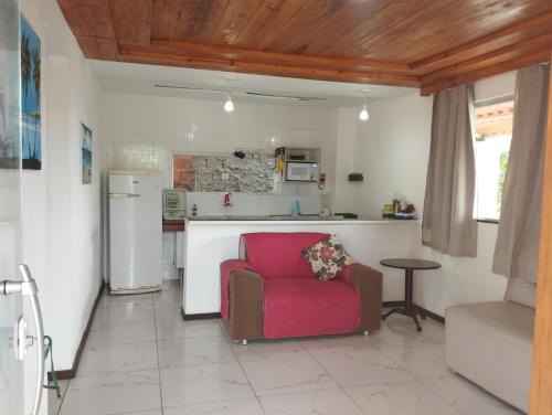 ein Wohnzimmer mit einem roten Stuhl und eine Küche in der Unterkunft Paraíso da Deise in Mata de Sao Joao