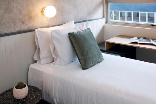 sypialnia z łóżkiem z białymi poduszkami i oknem w obiekcie Hotel TOTTO Wollongong w mieście Wollongong