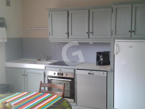 La cuisine est équipée de placards blancs, d'un réfrigérateur et d'une table. dans l'établissement Maison 6 pers à 200m de la plage du Rocher, La Tranche-sur-Mer – Confort et activités familiales - FR-1-357-234, à La Tranche-sur-Mer