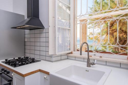 a white kitchen with a sink and a window at Villa Beachfront in Orebić