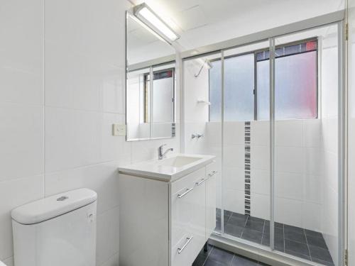 uma casa de banho branca com um lavatório e um chuveiro em Surfside Court - Hosted by Burleigh Letting em Gold Coast