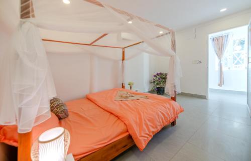 a bedroom with an orange bed with a canopy at Homestay Vuon Phap BMT in Buon Ma Thuot