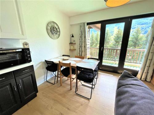 Il comprend un salon avec une table et une cuisine avec un balcon. dans l'établissement Studio pratique avec coin montagne à La Salle-les-Alpes, parking privatif - FR-1-330F-208, à La Salle Les Alpes