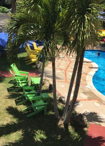 two palm trees and lounge chairs next to a pool at Hacienda de Flores in Guayacanes