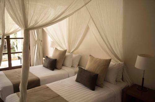 a bedroom with two beds with curtains and a window at Villa Alu Lima in Seminyak