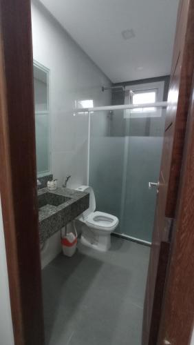 y baño con aseo, lavabo y ducha. en Apartamento Maresia en Morro de São Paulo