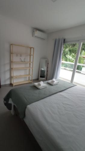 1 dormitorio con 1 cama blanca grande y ventana en Apartamento Maresia en Morro de São Paulo