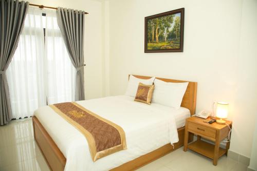 a bedroom with a bed and a table with a phone at BĂNG BOUTIQUE HOTEL in Thu Dau Mot