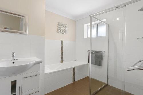 ein weißes Bad mit einem Waschbecken und einer Dusche in der Unterkunft Broadbeach Retreat 32 Broadbeach Drive in Carrickalinga